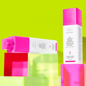 Drunk Elephant glycolic night serum bottles with pink caps displayed on colorful translucent blocks