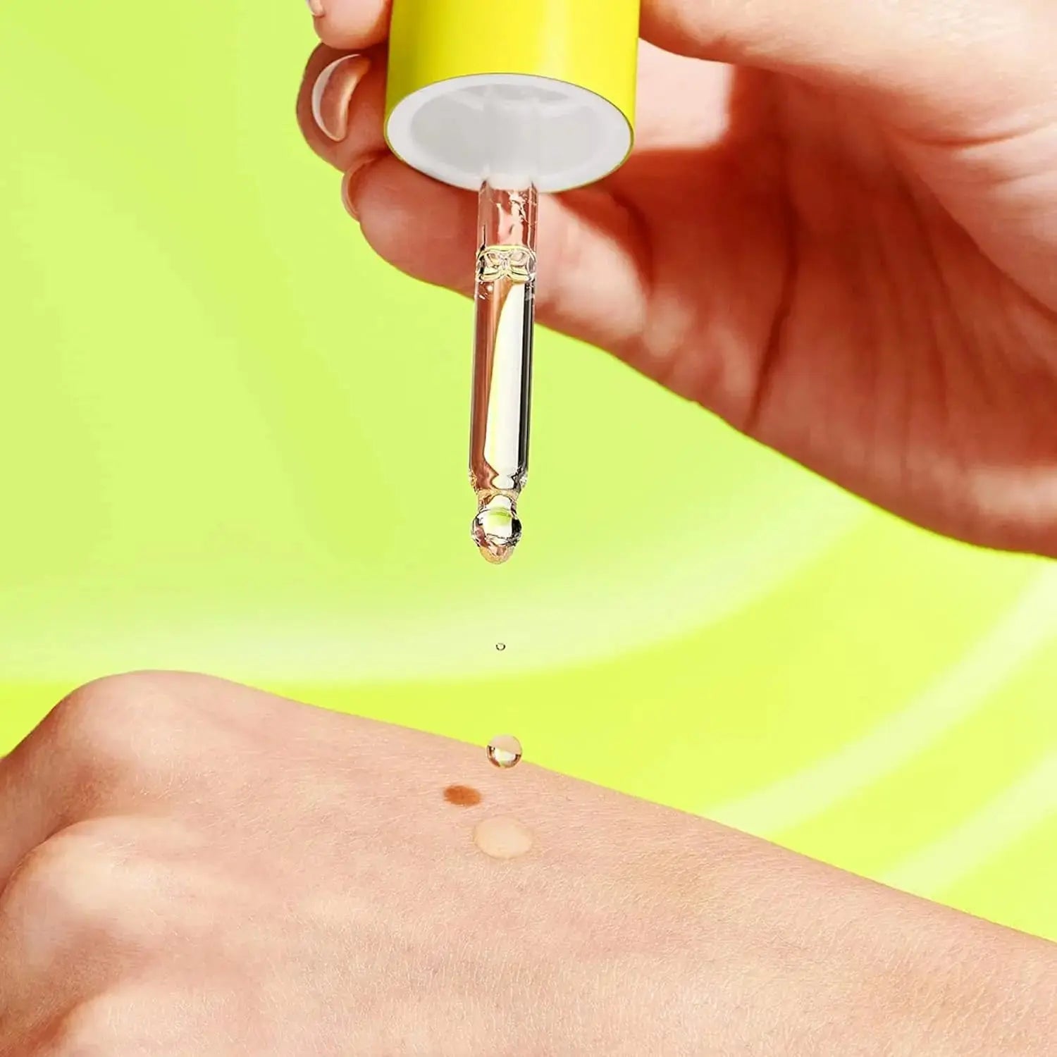Dripping dropper applying Drunk Elephant Virgin Marula Oil wholesale onto skin with bright green background