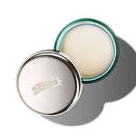 Open jar of La Mer lip balm with silver lid and soft balm inside on white background