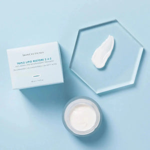 Skinceuticals Triple Lipid Restore 242 cream jar with product sample on clear hexagonal plate and blue box